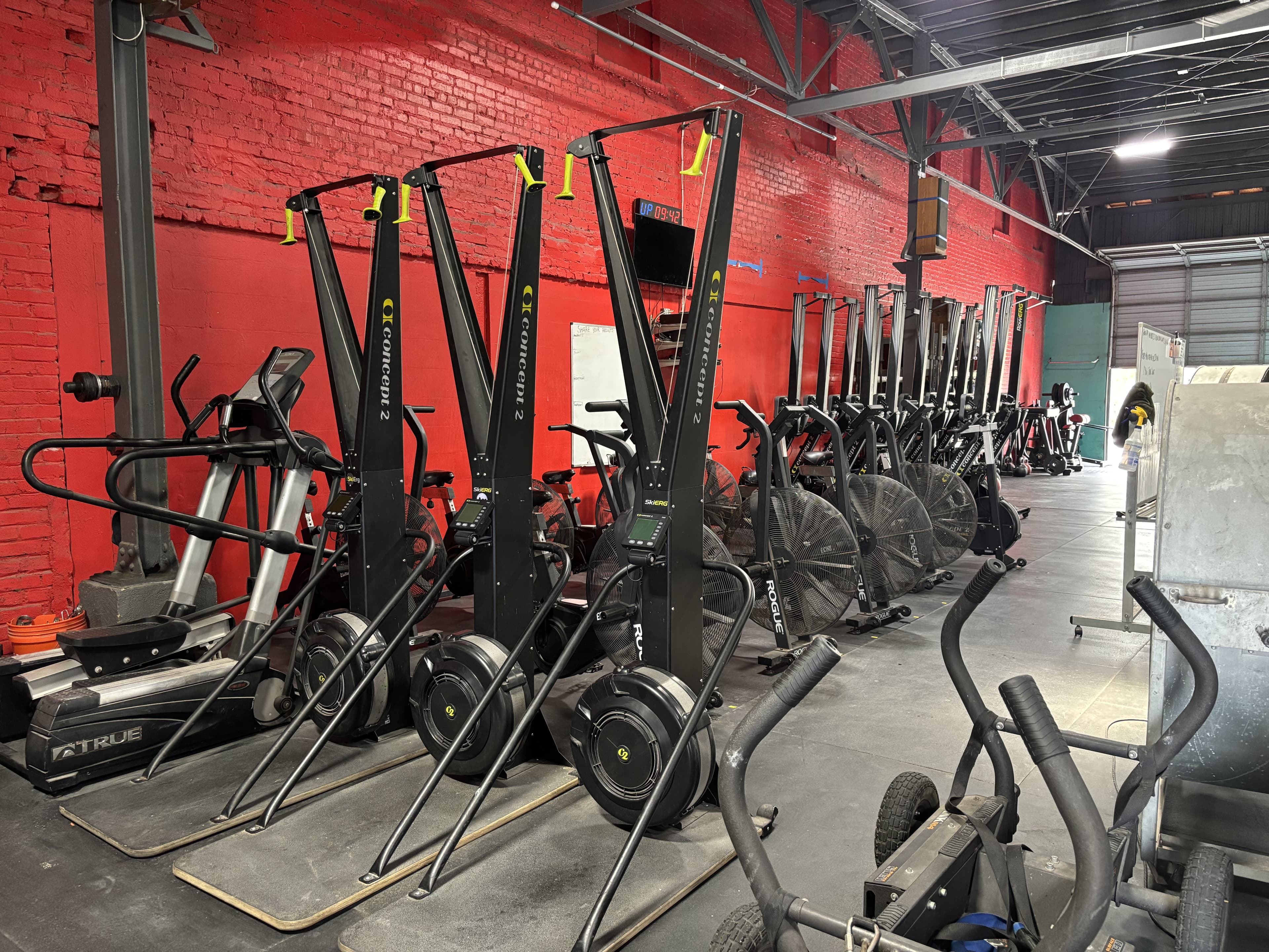 Row of SkiErgs and Echo bikes along the red wall at Havoc